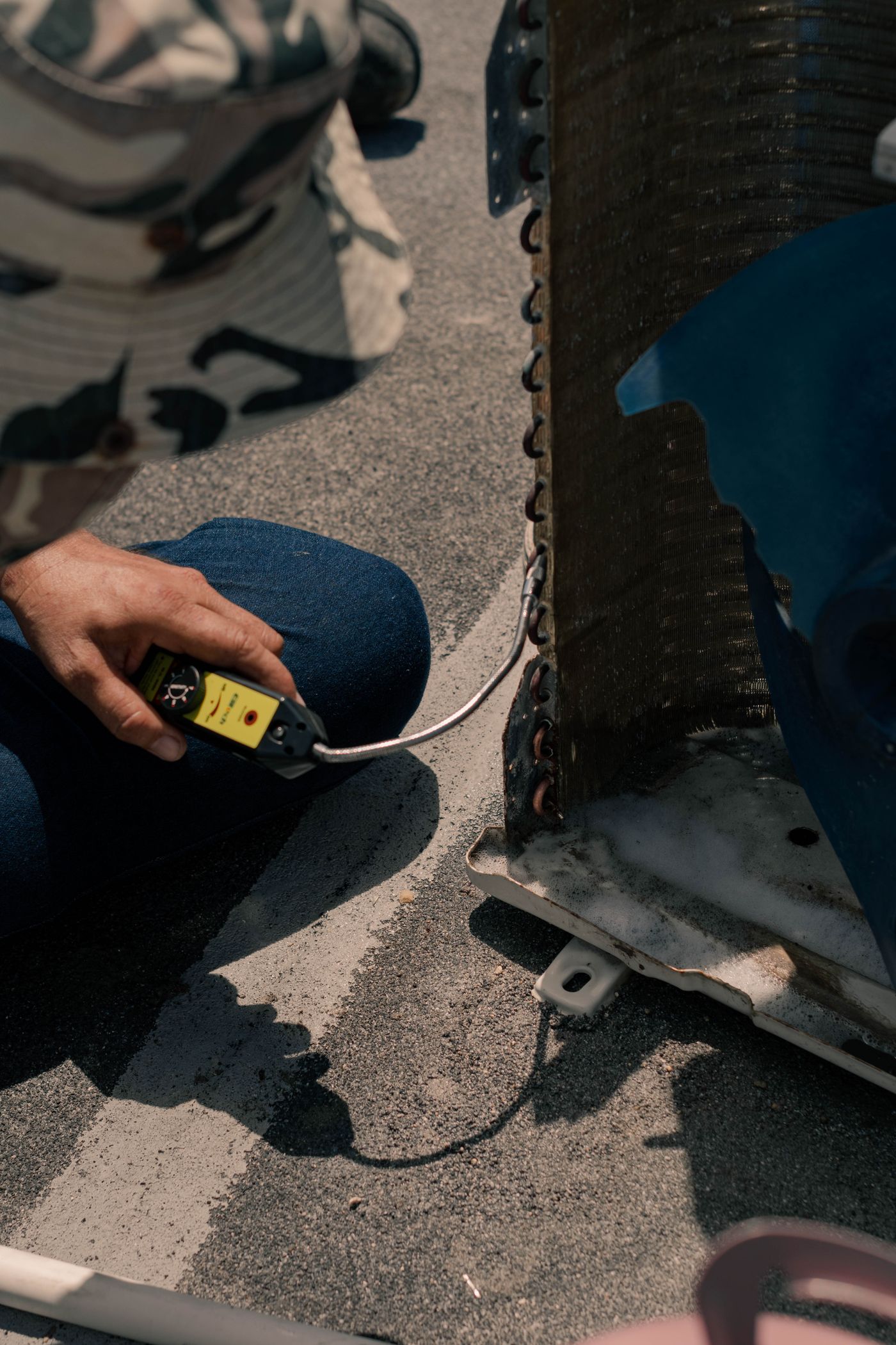 Technician inspecting an outdoor air conditioning unit with service gauges